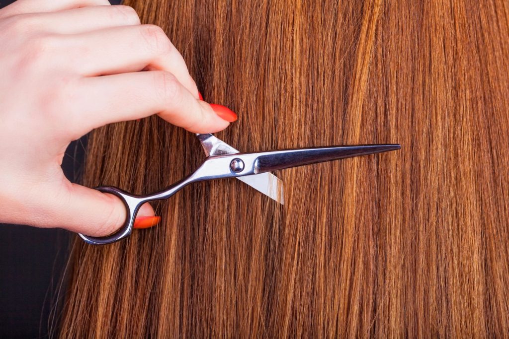 A person holding scissors on top of a wooden table.